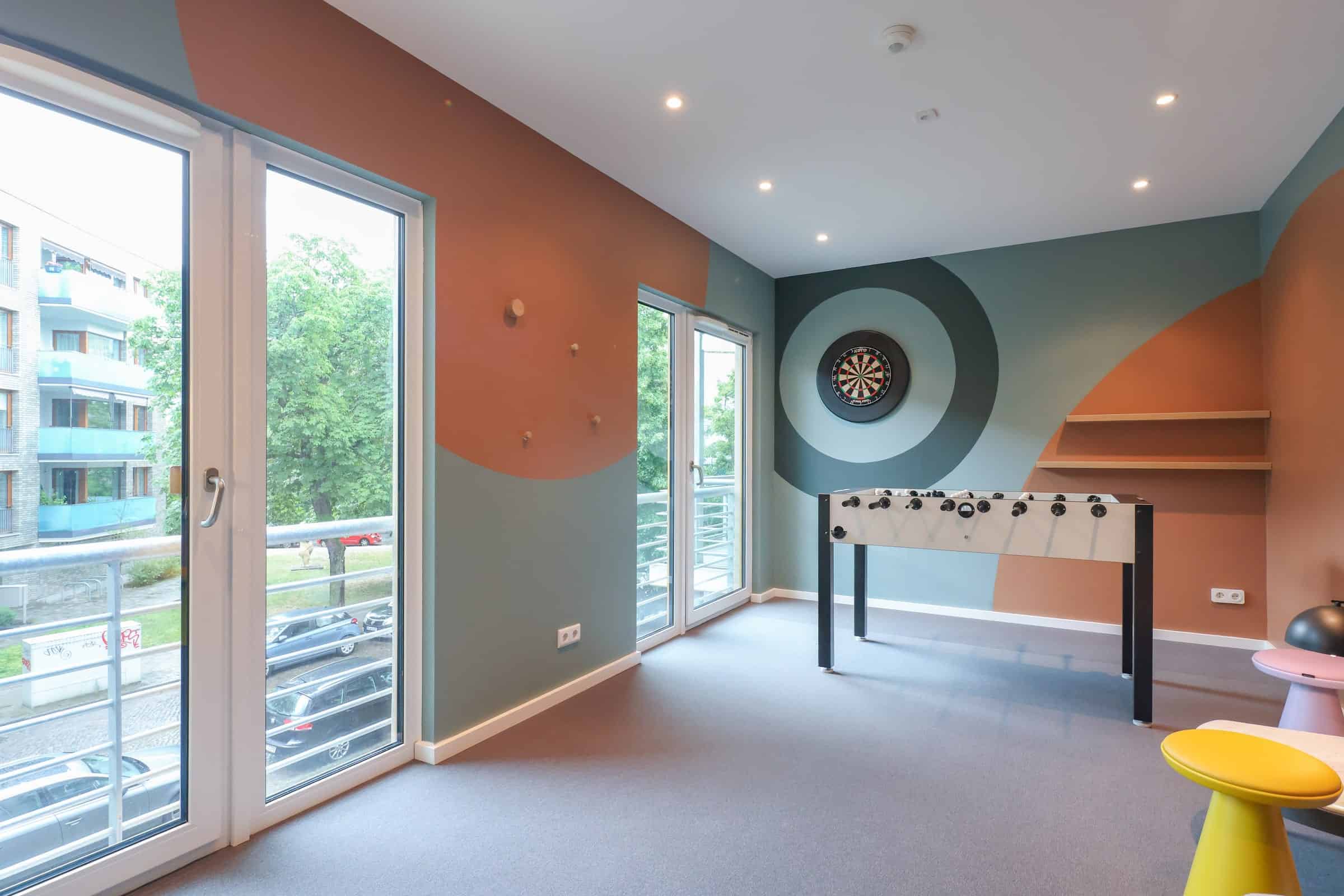 Gemeinschaftsraum im The Bloom Homes mit Kickertisch, Dartscheibe und Sitzecke