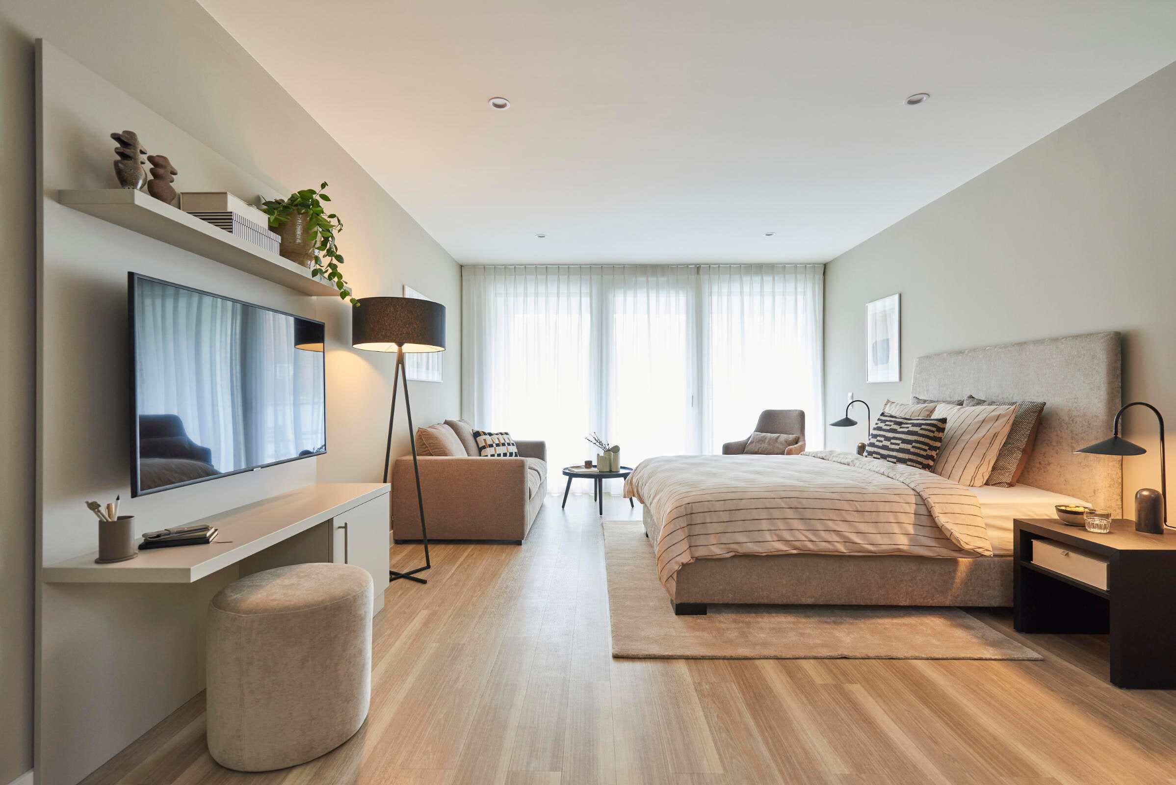 Wohn- und Schlafbereich eines Apartments im Roomments mit Fernseher und Schreibplatz