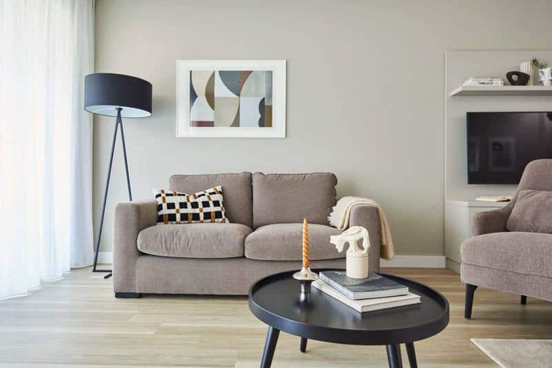 Wohnbereich mit Sofa, Couchtisch und Stehleuchte in einem Apartment im Roomments Stuttgart